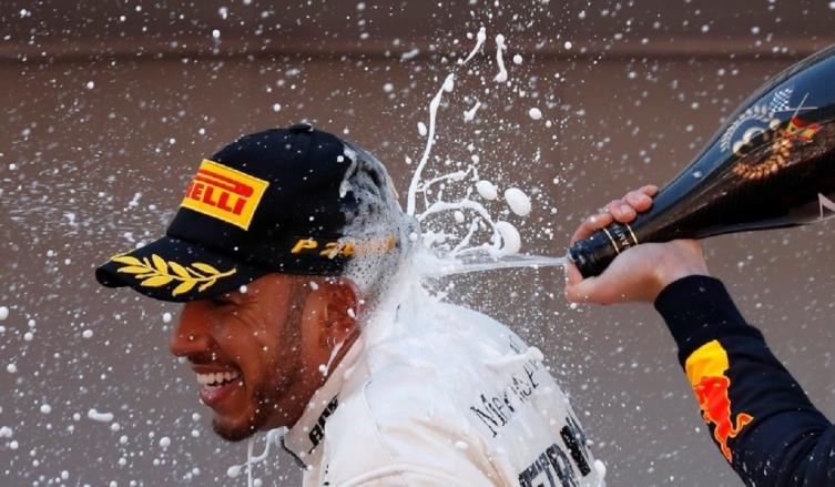 Hamilton recibe en la nuca el champagne para el vencedor, de manos de Verstappen. (Foto: AP)