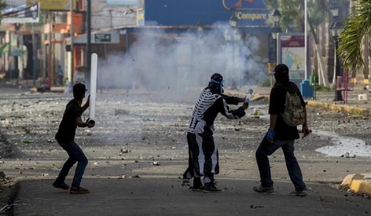 Tres jóvenes lanzan un mortero en un enfrentamiento con la Policía Nacional en la ciudad de Masaya. (EFE/Jorge Torres)