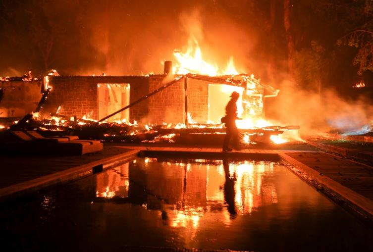 Un bombero en una casa en llamas, en Malibú (California). / AP