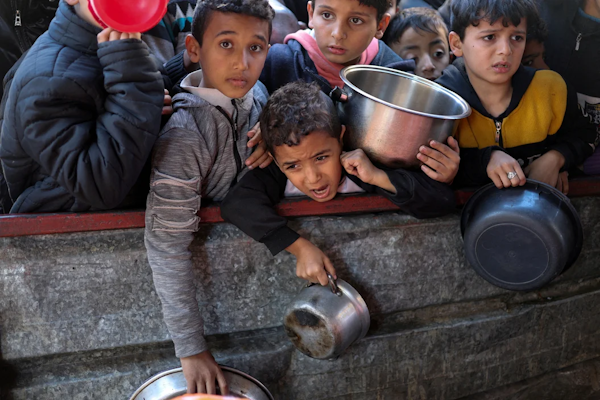 Niños palestinos esperan para recibir alimentos en una cocina de caridad en medio de la escasez de suministros de alimentos en Rafah. Foto: REUTERS/Ibraheem Abu Mustafa